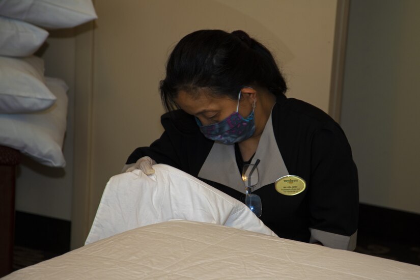 Ma Luisa Jones, Presidential Inn Housekeeping supervisor, makes a bed in one of the rooms at the Temporary Lodging Facility on Joint Base Andrews, Md., April 13, 2020. The Presidential Inn staff continue their daily routine with masks and gloves to protect themselves and others from COVID-19.