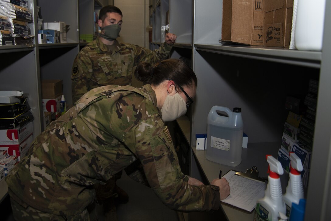 Staff Sgt. Joshua Grudznske, 11th Security Support Squadron supply NCO in-charge, and Senior Airman Caitlyn Truax, 11th SSPTS supply technician, verifies information on the sign out log for the hand sanitizer on Joint Base Andrews, Md., April 20, 2020. A sign out log is kept to track and ensure that units are able to get the supplies needed.