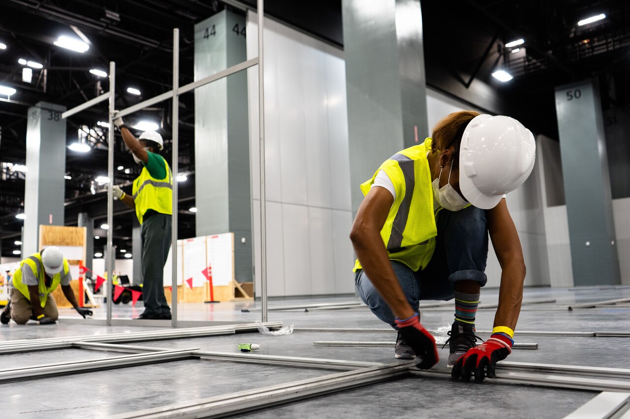 Construction crew members work in a large room.