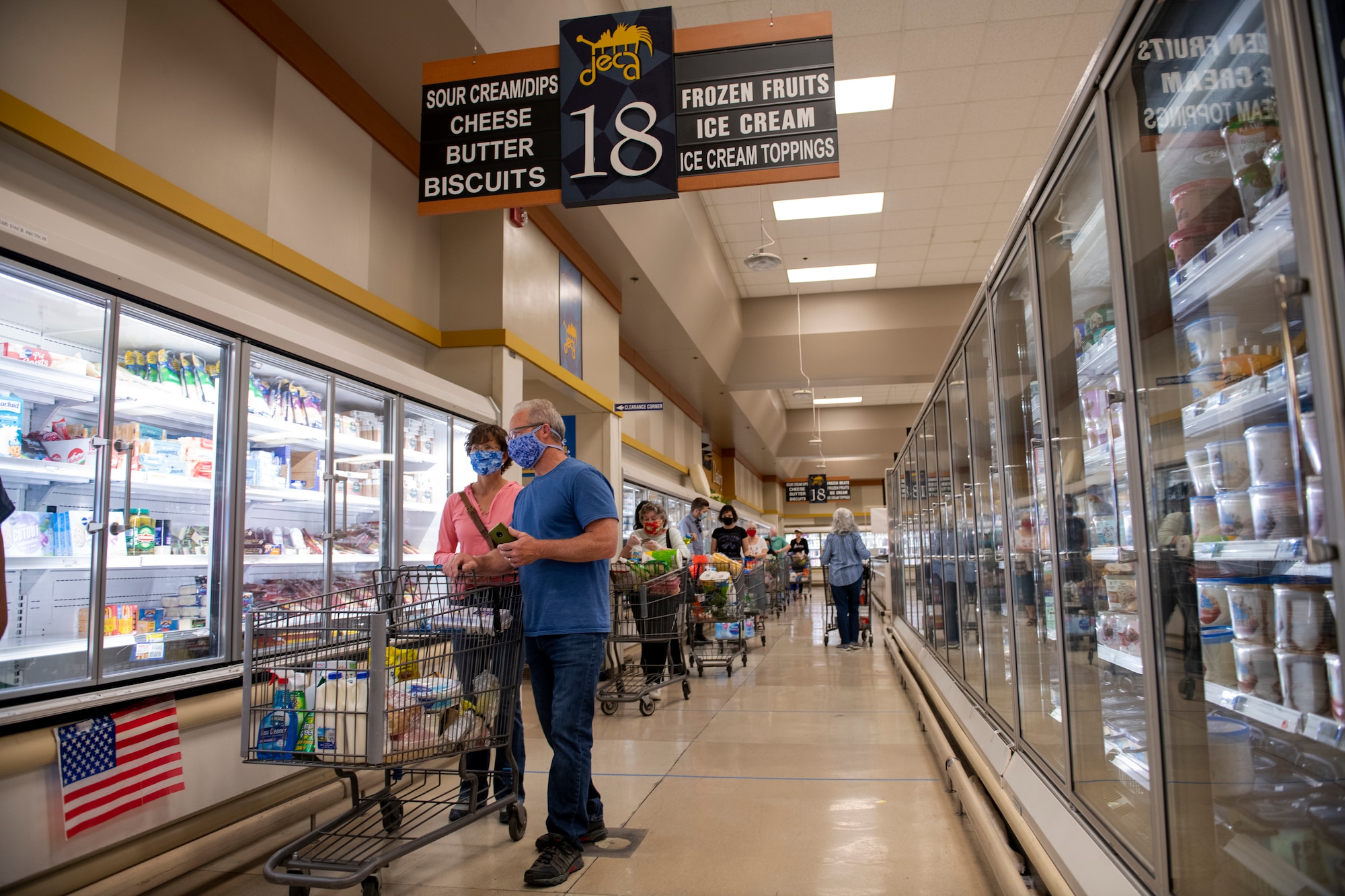 Shoppers wear masks as they wait to pay for their groceries April 16, 2020, inside the commissary at Travis Air Force Base, California. Commissary patrons must wear masks while shopping to prevent the spread of the new coronavirus. (U.S. Air Force photo by Tech. Sgt. James Hodgman)