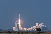 A rocket launches against a blue sky.