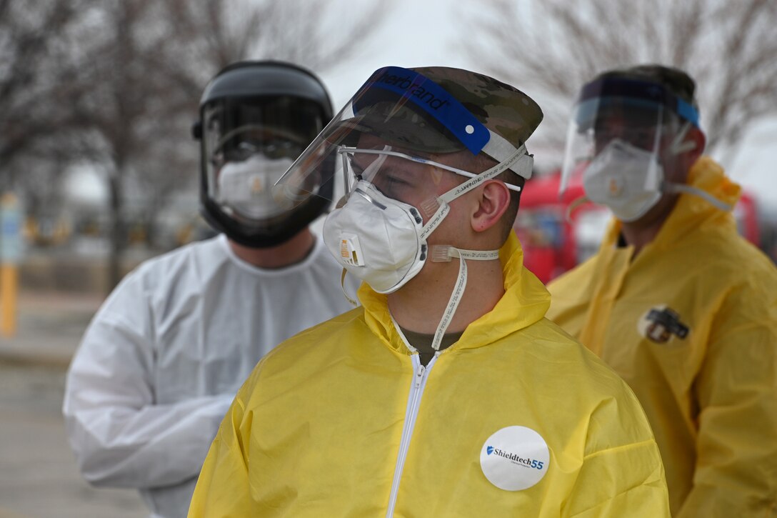 Photo of three North Dakota Air National Guard members wearing personal protective equipment as they prepare to administer COVID-19 tests to community volunteers going through the rapid testing site in the Alerus Center parking lot, Grand Forks, N.D., April 23, 2020.