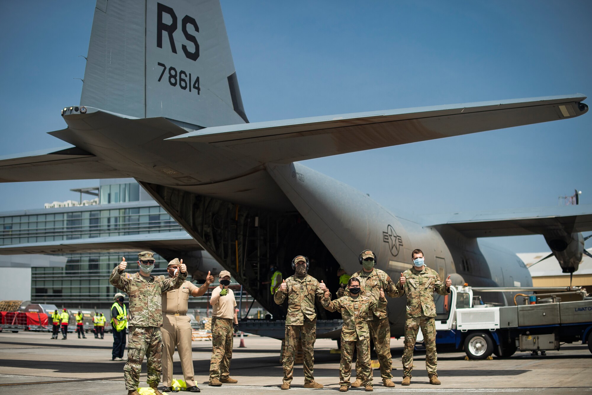 Airmen and Sailors stand by C-130 with COVID-19 medical supplies.
