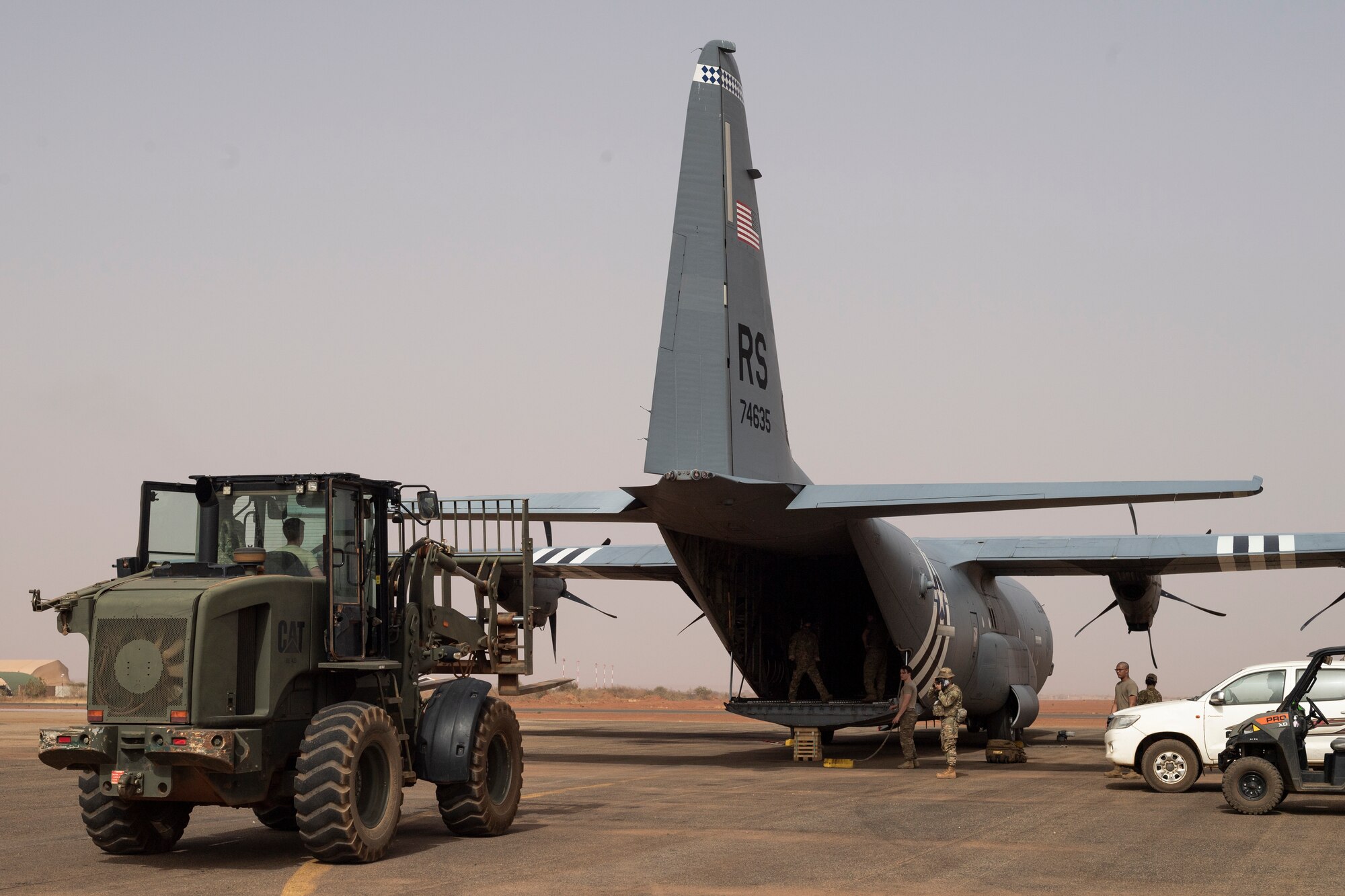 Airman driving a forklift unloads cargo from a C-130.