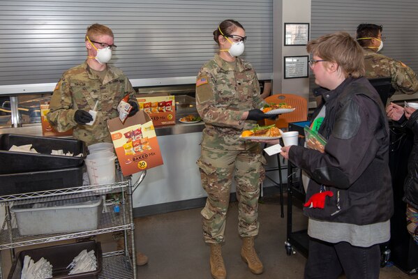U.S. Army Pvt. Harold Taylor and Spc. Jo England, communications operators, 1st Battalion 157th Infantry Regiment, Colorado Army National Guard serve food to the guests at the Denver Rescue Mission, April 20, 2020. The Soldiers helped a man who was choking on food.