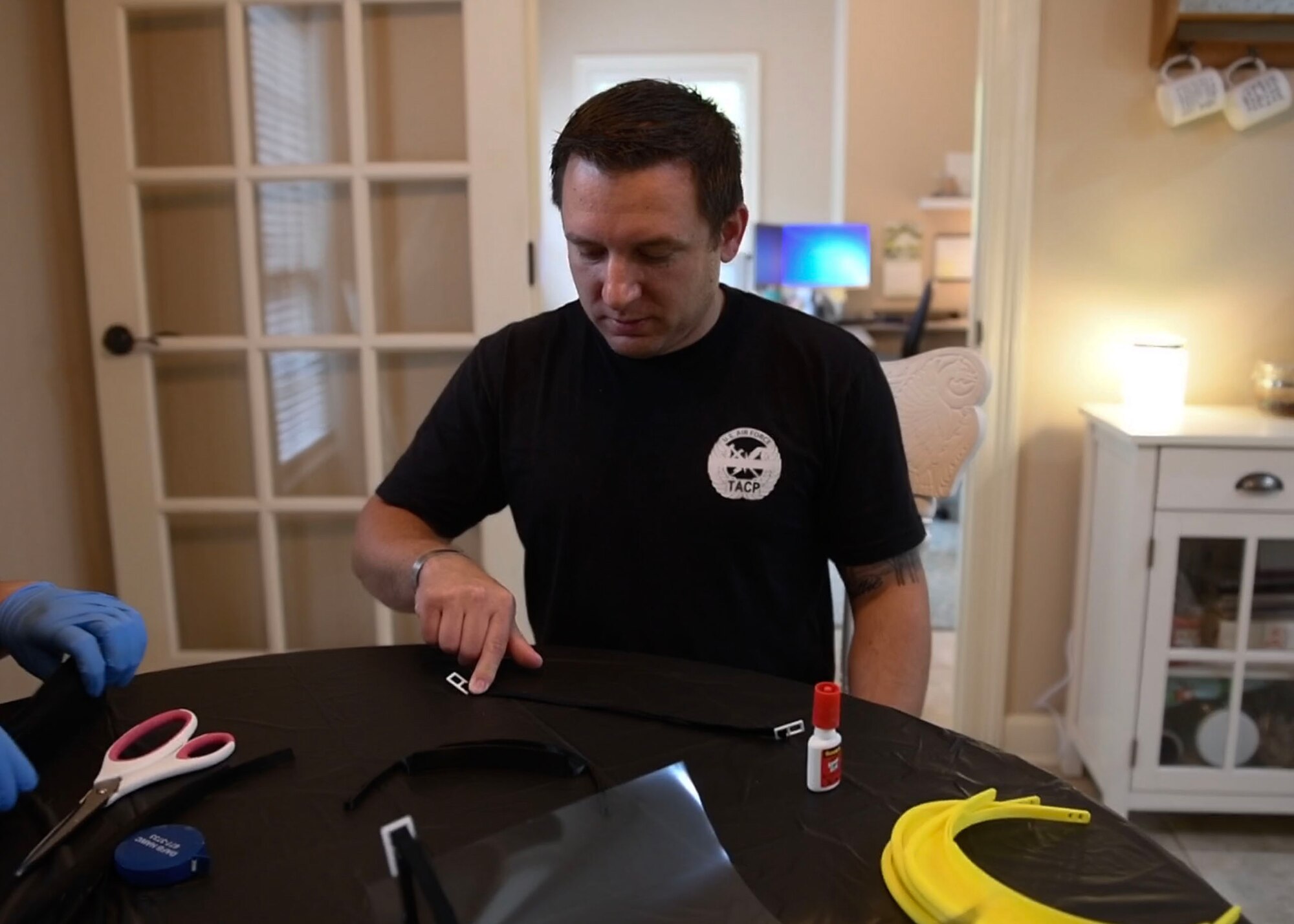 A man sits at a table with his finger holding down a strap.