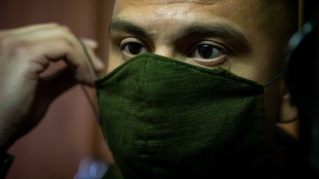 A close-up of a marine putting a cloth mask on their face