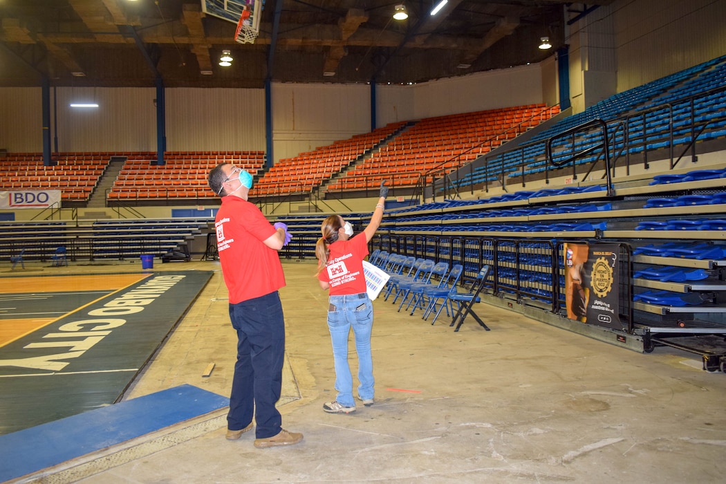 USACE employees pointing at the ceiling while standing at the floor of the coliseum