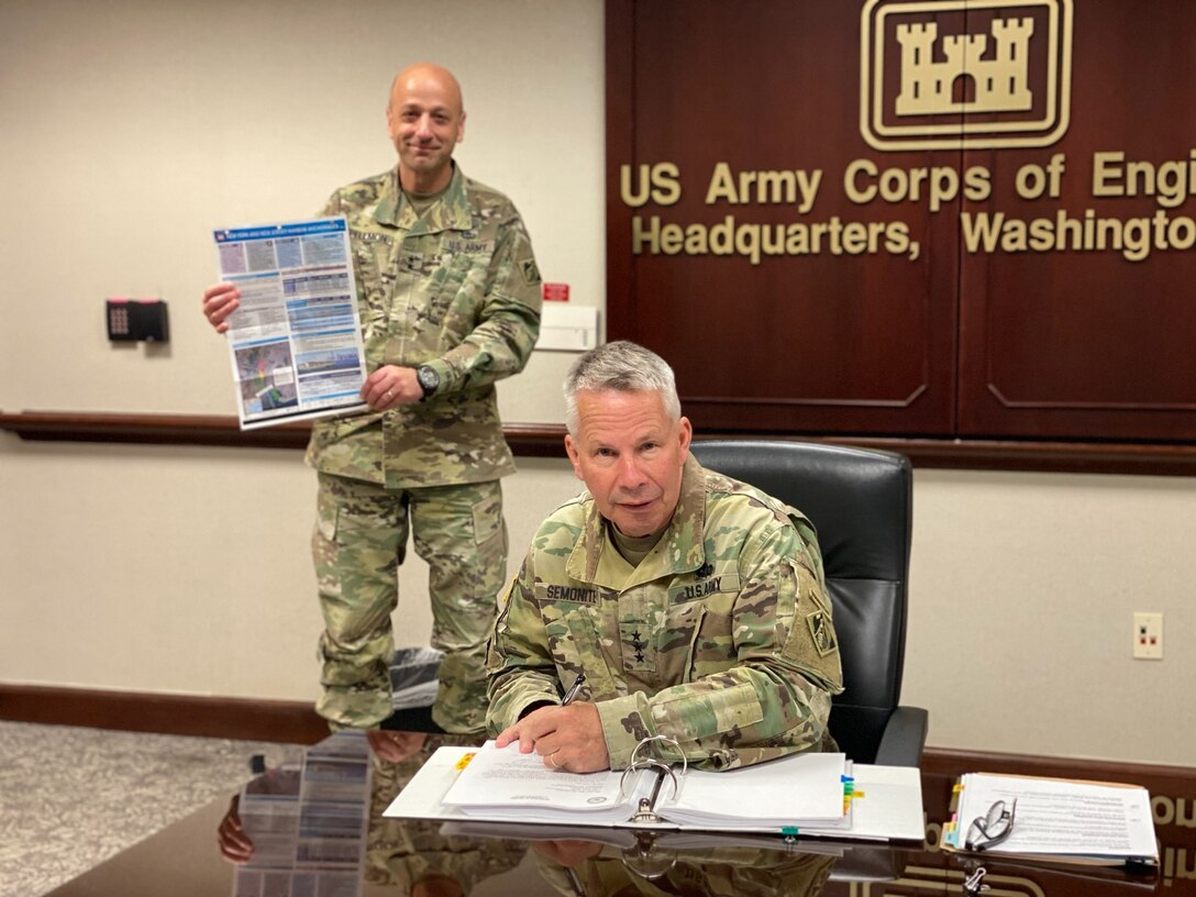 Lt. Gen. Todd Semonite, chief of engineers and U.S. Army Corps of Engineers commanding general, signs a Chief’s Report for the New York and New Jersey Harbor Anchorages Study at headquarters in Washington, April 23, 2020. Holding up the study’s placemat is Maj. Gen. Scott Spellmon (background), USACE deputy commanding general for civil and emergency operations.