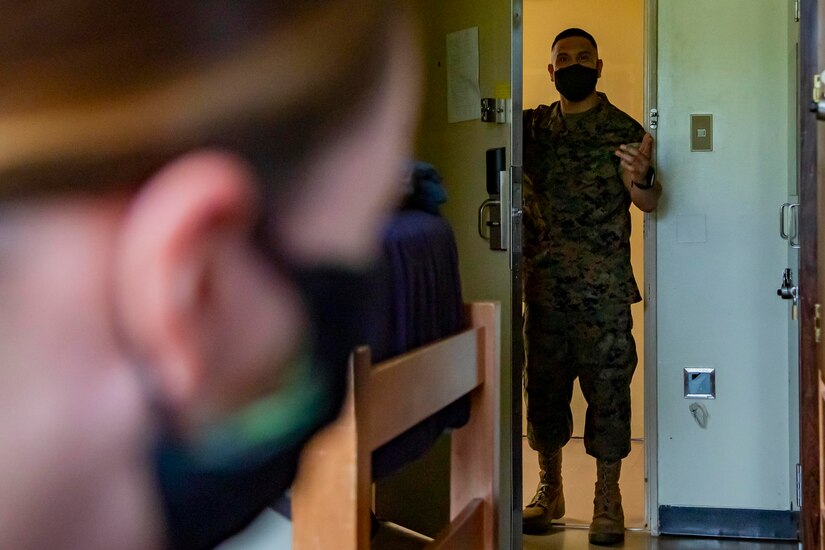 A Marine opens a barracks room door to check up on one of his Marines.