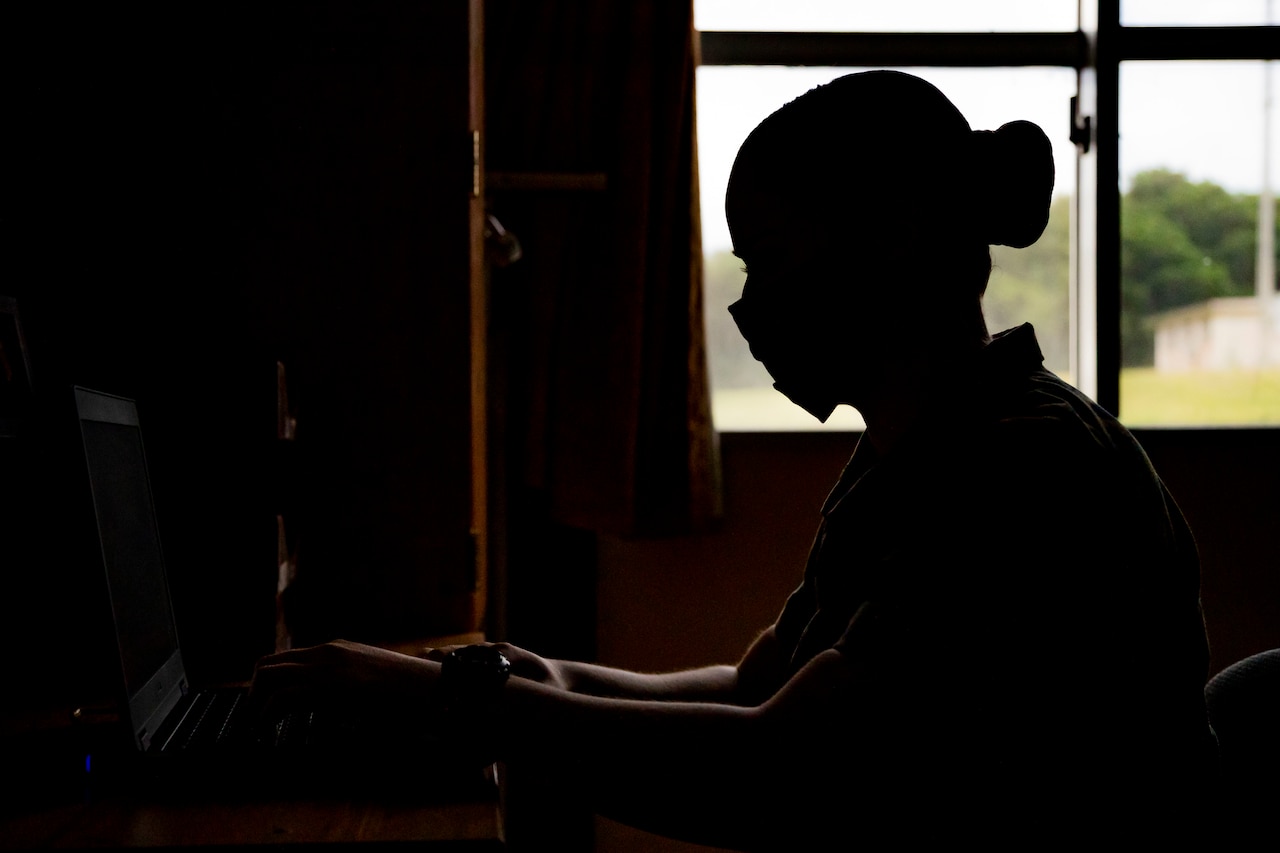 A Marine teleworks from her laptop while sitting at her desk.