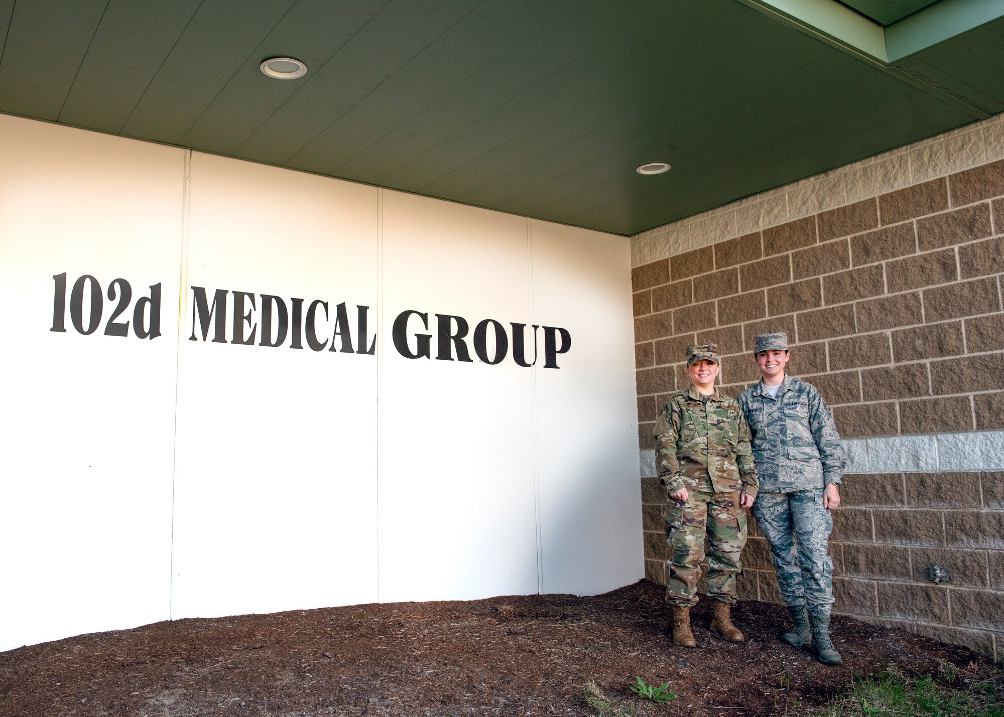 Two Airmen from Public Health stand in front of the 102nd Medical Group building at Otis Air National Guard Base, Mass.