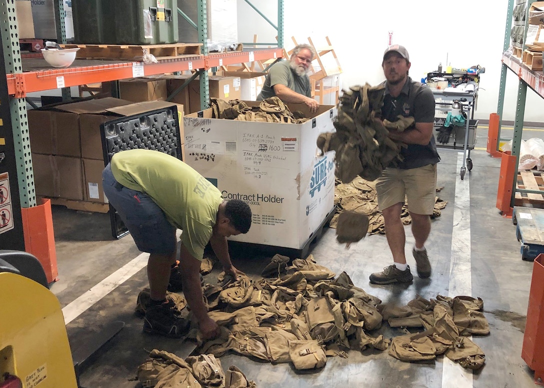 Colin Light (rear), Brian Licht (center) and Paul Turner (front), count pouches for carrying first aid supplies turned in at Camp Lejeune, North Carolina, during the first wall-to-wall inventory of all DLA Disposition Services sites.