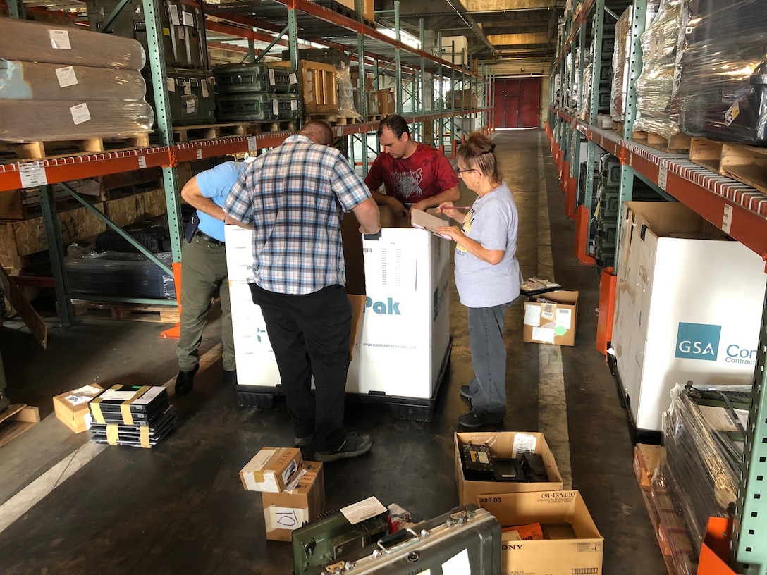 Tommy Martorana (left), Lucas Grant (left center) and Robert Repasi (right center) check through items in a container at Camp Lejeune, North Carolina, as Sharon “Cher” Burke (right) tracks the information during the first wall-to-wall inventory of all DLA Disposition Services sites.