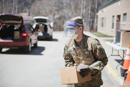 Sgt. Zachary Paquin, a fire directions specialist with the New Hampshire Army National Guard, distributes food at a mobile food drive at in Colebrook, N.H.