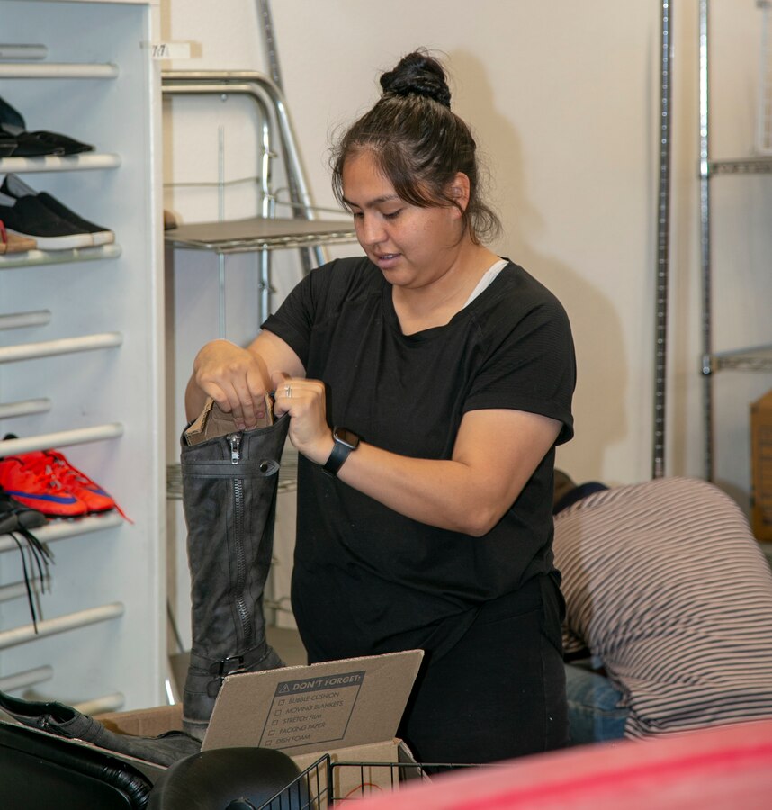 Cpl Ana Santiago, inspector clerk with the Command Inspector General’s Office, prepares a boot for display during the NMCRS Thrift Store move in April 18. Santiago was one of about 20 Marines and civilians who volunteered their time to assist with the relocation.