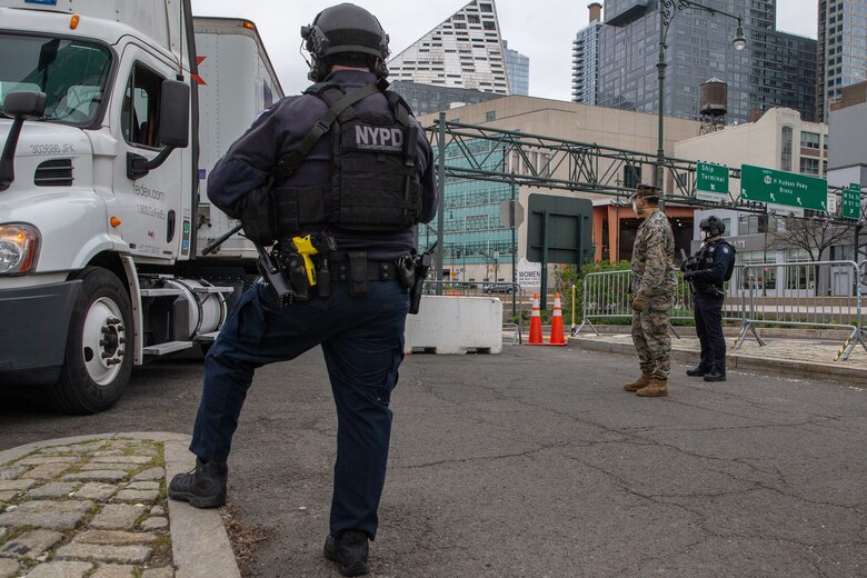 Lance Cpl. Matthew Aquino, a rifleman with Lima Company, 3rd Battalion, 2nd Marine Regiment, Task Force New York, and police officers with the Critical Response Command in the Counterterrorism Bureau of the New York City Police Department post security for the hospital ship USNS Comfort (T-AH 20) in New York City, April 23, 2020. Comfort cares for trauma, emergency and urgent care patients without regard to their COVID-19 status. Comfort is working with the Javits New York Medical Station as an integrated system to relieve the New York City medical system, in support of U.S. Northern Command's Defense Support of Civil Authorities as a response to the COVID-19 pandemic. (U.S. Marine Corps photo by Sgt. Stormy Mendez)