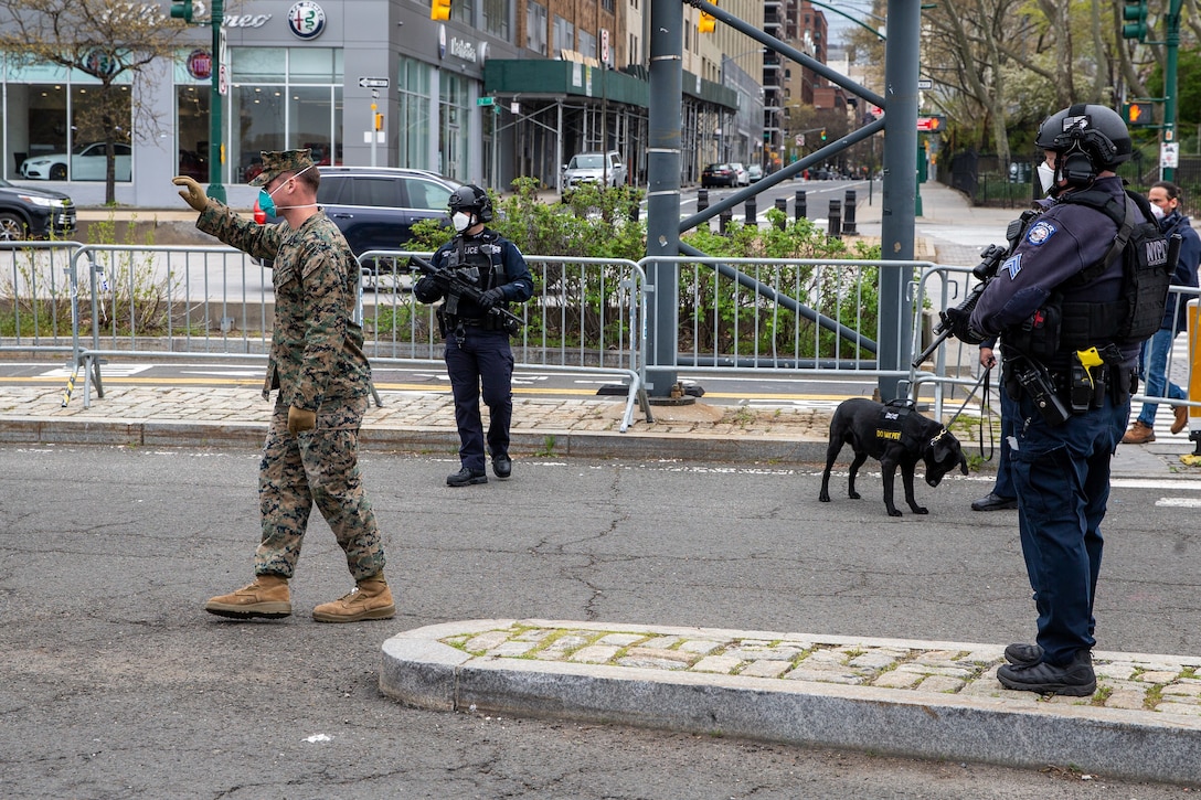Cpl. Timothy Pennington, a rifleman with Lima Company, 3rd Battalion, 2nd Marine Regiment, Task Force New York, guides a vehicle while police officers with the Critical Response Command in the Counterterrorism Bureau of the New York City Police Department stand security for the hospital ship USNS Comfort (T-AH 20) in New York City, April 23, 2020. Comfort cares for trauma, emergency and urgent care patients without regard to their COVID-19 status. Comfort is working with the Javits New York Medical Station as an integrated system to relieve the New York City medical system, in support of U.S. Northern Command's Defense Support of Civil Authorities as a response to the COVID-19 pandemic. (U.S. Marine Corps photo by Sgt. Stormy Mendez)