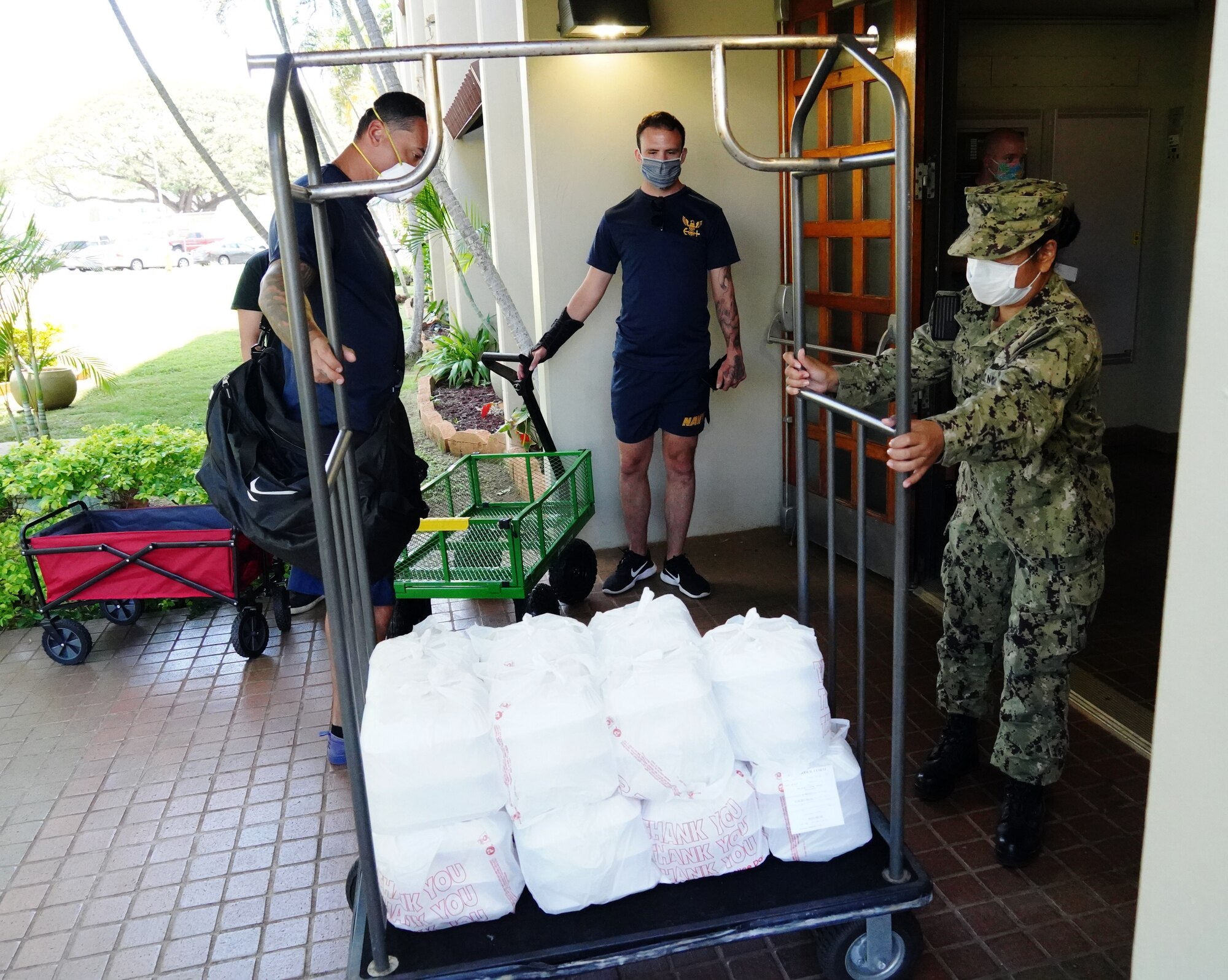 U.S. Navy Sailors deliver meals from the Hale Aina Dining Facility to newly arrived personnel placed on restriction of movement on Joint Base Pearl Harbor-Hickam, Hawaii, April 16, 2020. Volunteers with the COVID-19 Support Team distributed meals and essentials to ROM military personnel in the midst of the COVID-19 pandemic. (U.S. Air Force photos by Airman 1st Class Erin Baxter)