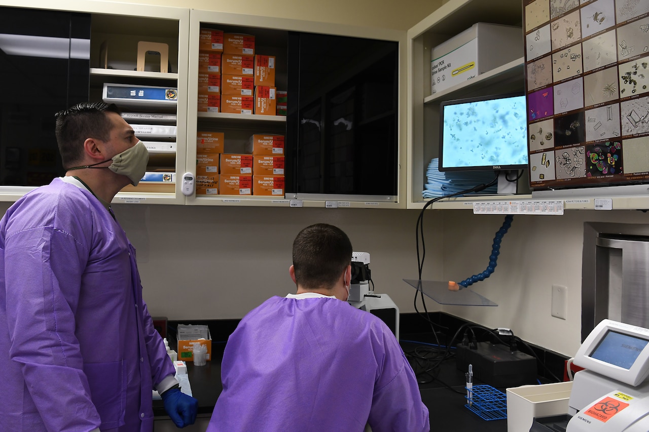 Airmen using a microscope.
