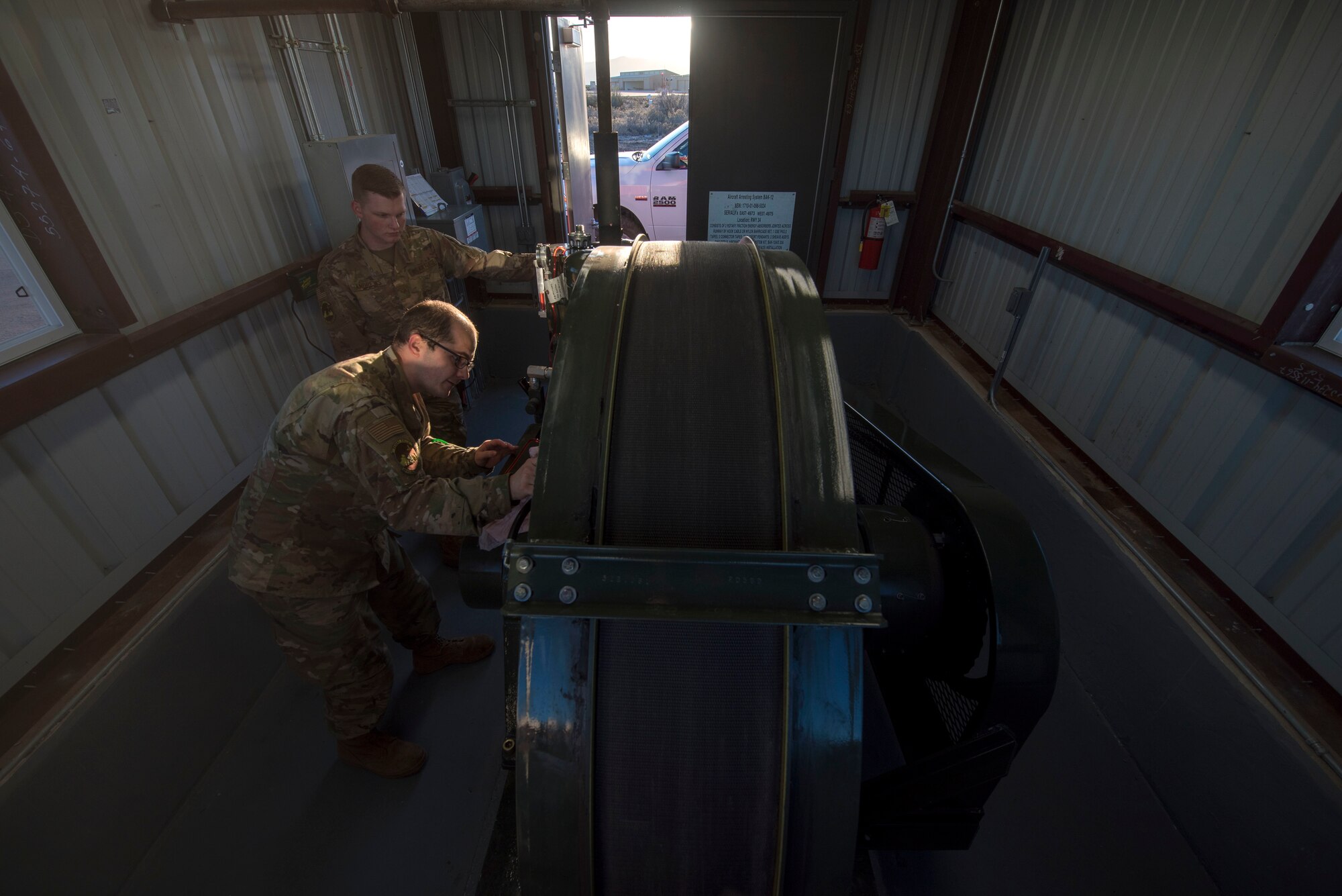 Senior Airman Wyatt Andrews and Airman 1st Class Curtis Mark, 49th Civil Engineer Squadron electrical power production technicians, perform weekly maintenance and inspections on a BAK-12 Aircraft Arresting System on the flightline, on Holloman Air Force Base, N.M., April 21, 2020. During weekly inspections, Airmen bleed brakes of air and ensure hydraulic pressure is applied to slow down an aircraft safely in an emergency. (U.S. Air Force photo by Staff Sgt. Christine Groening)