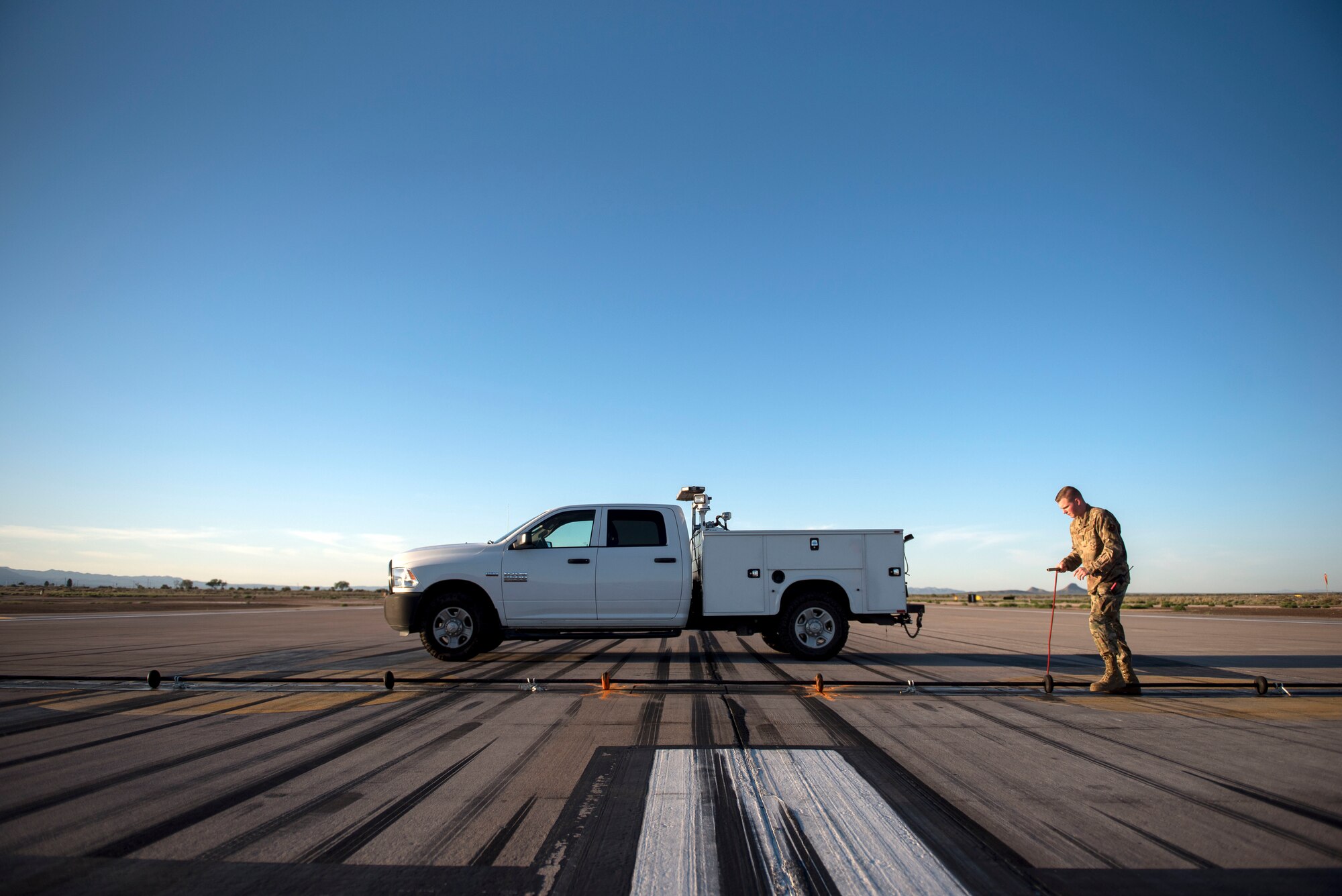 Senior Airman Wyatt Andrews, 49th Civil Engineer Squadron electrical power production technician, separates support disks on a barrier system cable on the flightline, on Holloman Air Force Base, N.M., April 21, 2020. The disks are spaced six to eight inches apart and raised two inches off the ground to engage the tailhook off of an aircraft in the event of an emergency. (U.S. Air Force photo by Staff Sgt. Christine Groening)