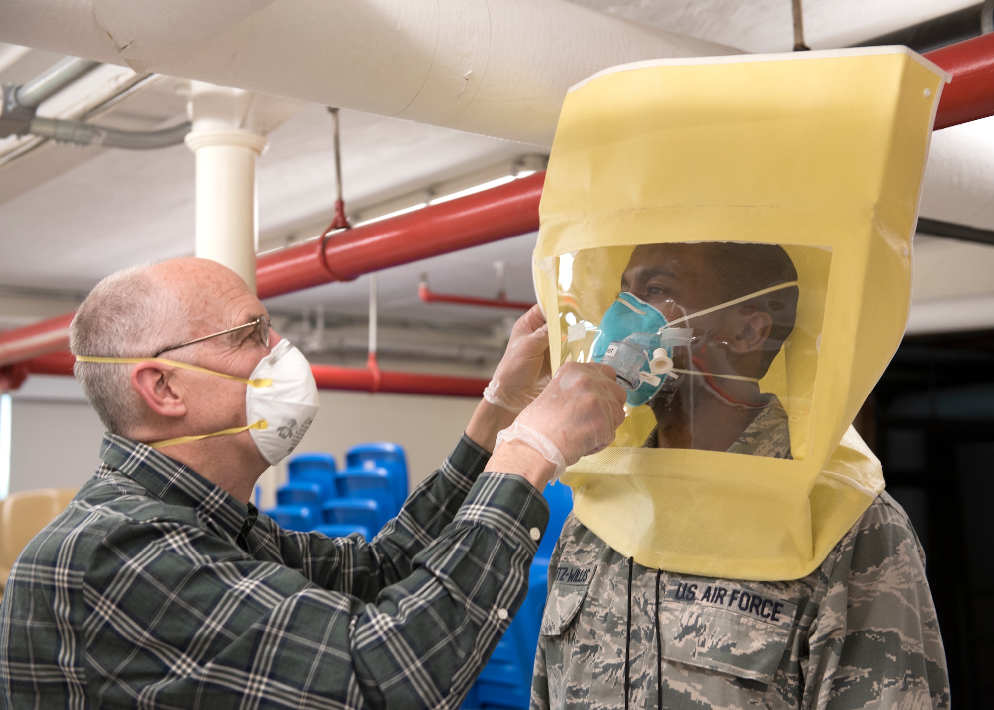 An Airman conducts a mask fitting test with a force health protection officer