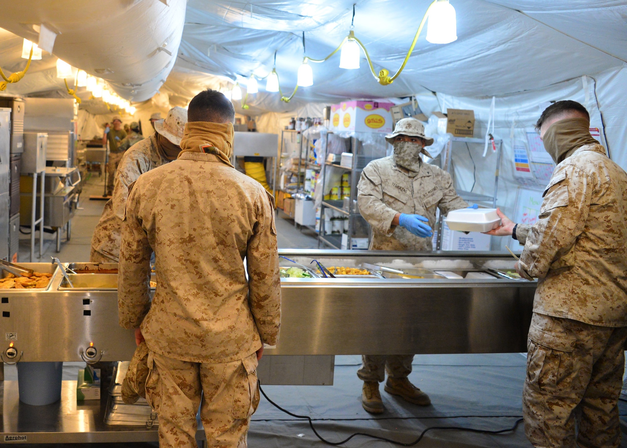 U.S. Marines serve patrons food as volunteers at the Sandstorm field kitchen, Ahmed Al Jaber Air Base, Kuwait, April 17, 2020. The 407th Air Expeditionary Group stood up the Sandstorm as a way to balance health protection levels and further support installation inhabitants by providing an additional avenue for customers to have a meal. (U.S. Air Force photo by Senior Airman Isaiah J. Soliz)