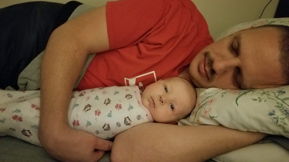 Photo of a dad and baby lying in bed