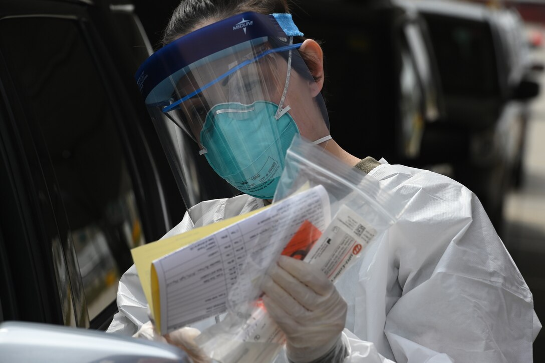 Photo of Staff Sgt. Misty Poitra, of the 119th Medical group, gathering data and swab samples for testing of people who are volunteering to drive through a rapid testing process in the FargoDome parking lot, Fargo, N.D., April 25, 2020. She wearing personal protective equipment (PPE) to stay safe while she works and helps prevent the spread of the Coronavirus while testing people as they drive through the process in their vehicles.