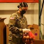 North Carolina National Guard Spc. Dena Arnold of Delta Company, 1-130th Attack Reconnaissance Battalion, 449th Theater Aviation Brigade, sorts produce for distribution to local food banks at the Food Bank of Central and Eastern North Carolina in Raleigh, N.C., April 27, 2020.