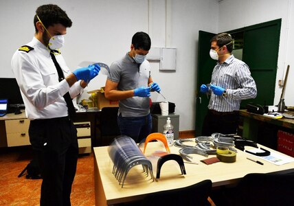 Miguel Angel Garcia (left), a Spanish Armada functionary; Milton Perez-Cruz (center), a mechanical engineer from Naval Surface Warfare Center Carderock Division; and David Sanchez, a Spanish Armada engineer, assemble face shields produced in their additive manufacturing lab at the Forward Deployed Regional Maintenance Center Detachment Rota, Spain, in April 2020 for use at local hospitals during the COVID-19 pandemic.