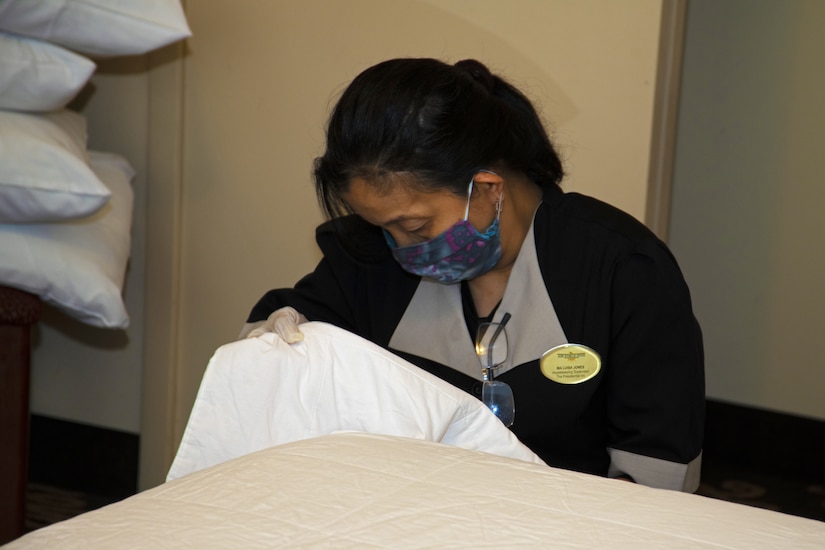 A housekeeper makes a bed.