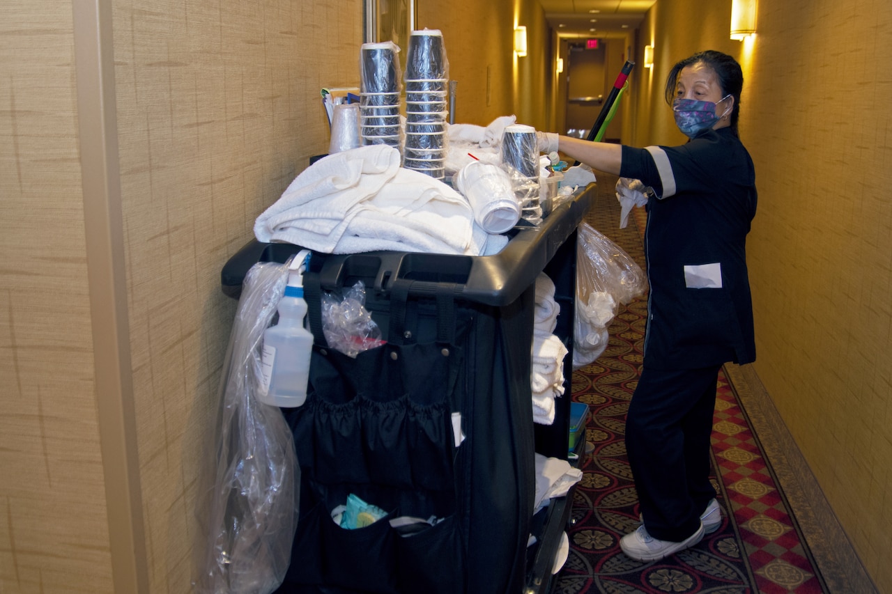 A housekeeper removing supplies from a cleaning cart.