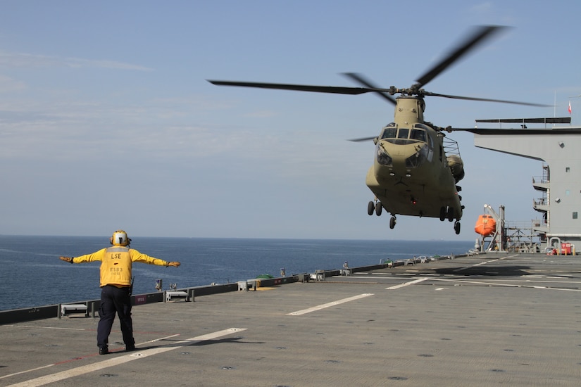 A Chinook is directed to land on the deck of the U.S.S. Lewis B. Puller during a training exercise on April 15, 2020 in the Persian Gulf. The U.S. Army and the U.S. Navy work together to increase both their forces capabilities during a training exercise. (U.S. Army photo by SGT. Andrew Winchell)