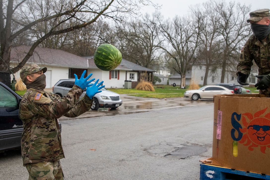 A soldier tosses a watermelon to another soldier.