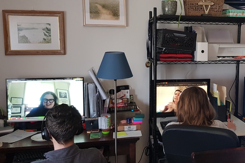 A boy and a girl sit next to each other and work on computers.