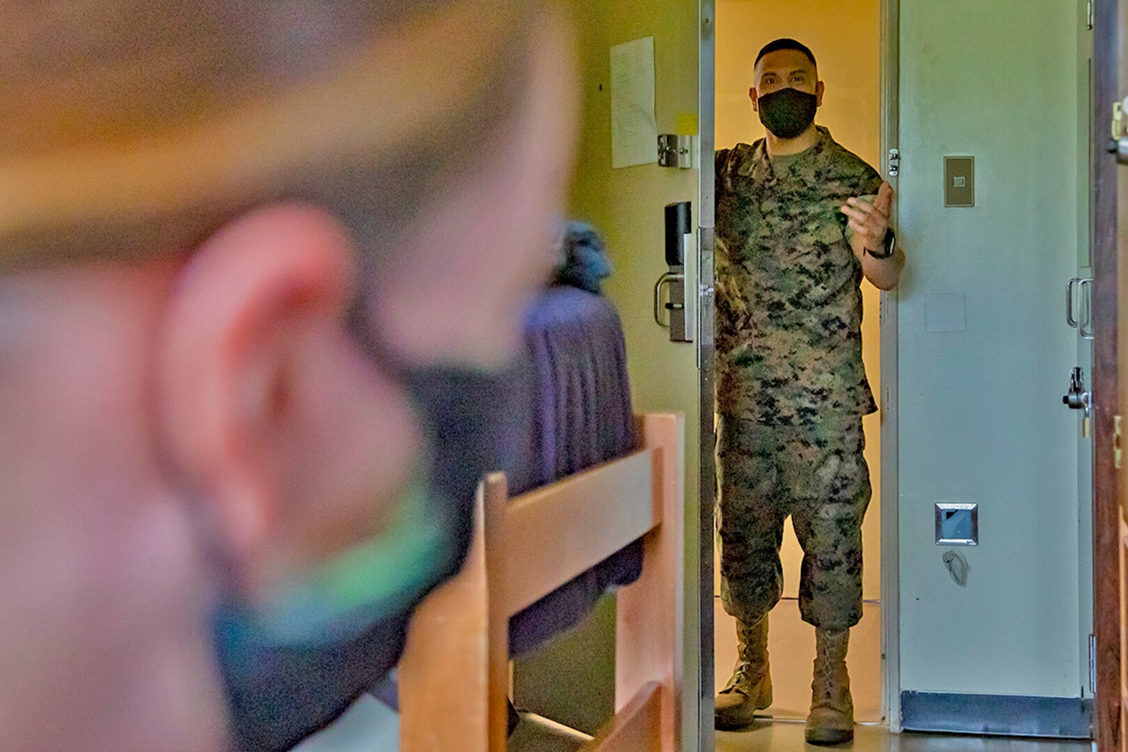 A Marine does a room check on one of his fellow Marines.