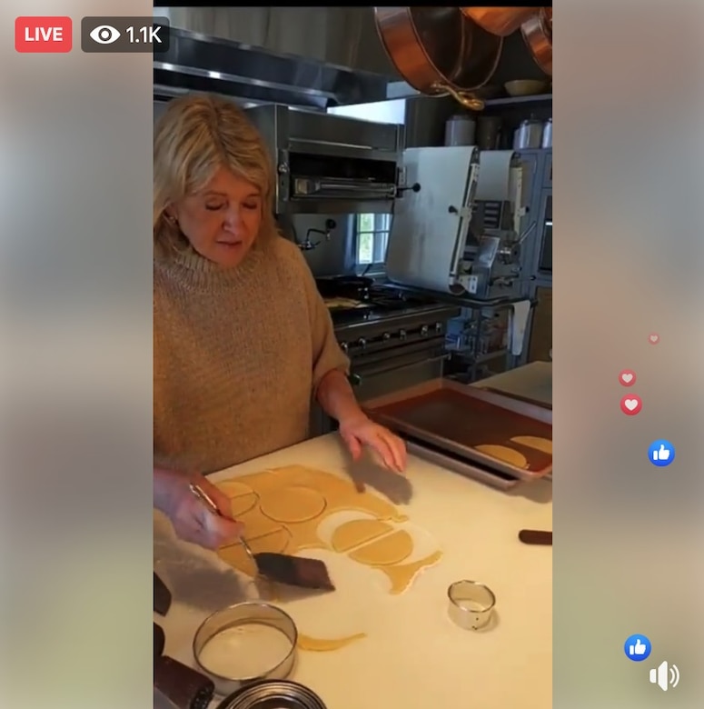 A screenshot of a woman putting unbaked cookies onto a pan.