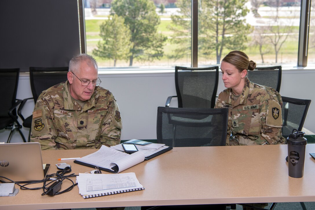 U.S. Air Force Lt. Col. Richard Kane, Arapahoe County Task Force Emergency Operations Center commander, and Army Sgt.1st Class Heather Long, noncommissioned officer in charge, participate in a morning conference call with other EOC team members April 8 in Centennial, Colo. Members of the Colorado National Guard volunteer to support state and local officials combat the COVID-19 pandemic by assisting state and local emergency operations centers state wide, setting up a joint operations center and preparing shelters for those without homes in the Denver area.