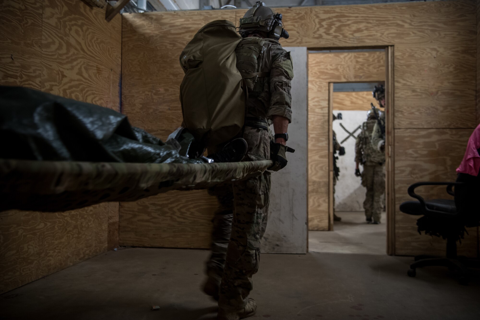 An Air Force Special Tactics operator carries a patient on a stretcher to evacuate during an operability training scenario at Eglin Range, Florida