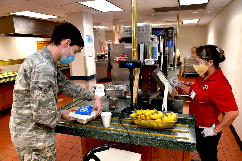 Airman 1st Class Logan Parent, 388th Aircraft Maintenance Squadron, pays for a meal with Angie Skeen, Hillcrest Dining Facility food services, at the Hill Air Force Base, Utah, April 23, 2020. The food services contractor, Native Resource Development Company, Inc., is continuing to provide carry out meals for the base’s Airmen during the COVID-19 pandemic while keeping the dining facility extra clean and sanitized. (U.S. Air Force photo by Todd Cromar)