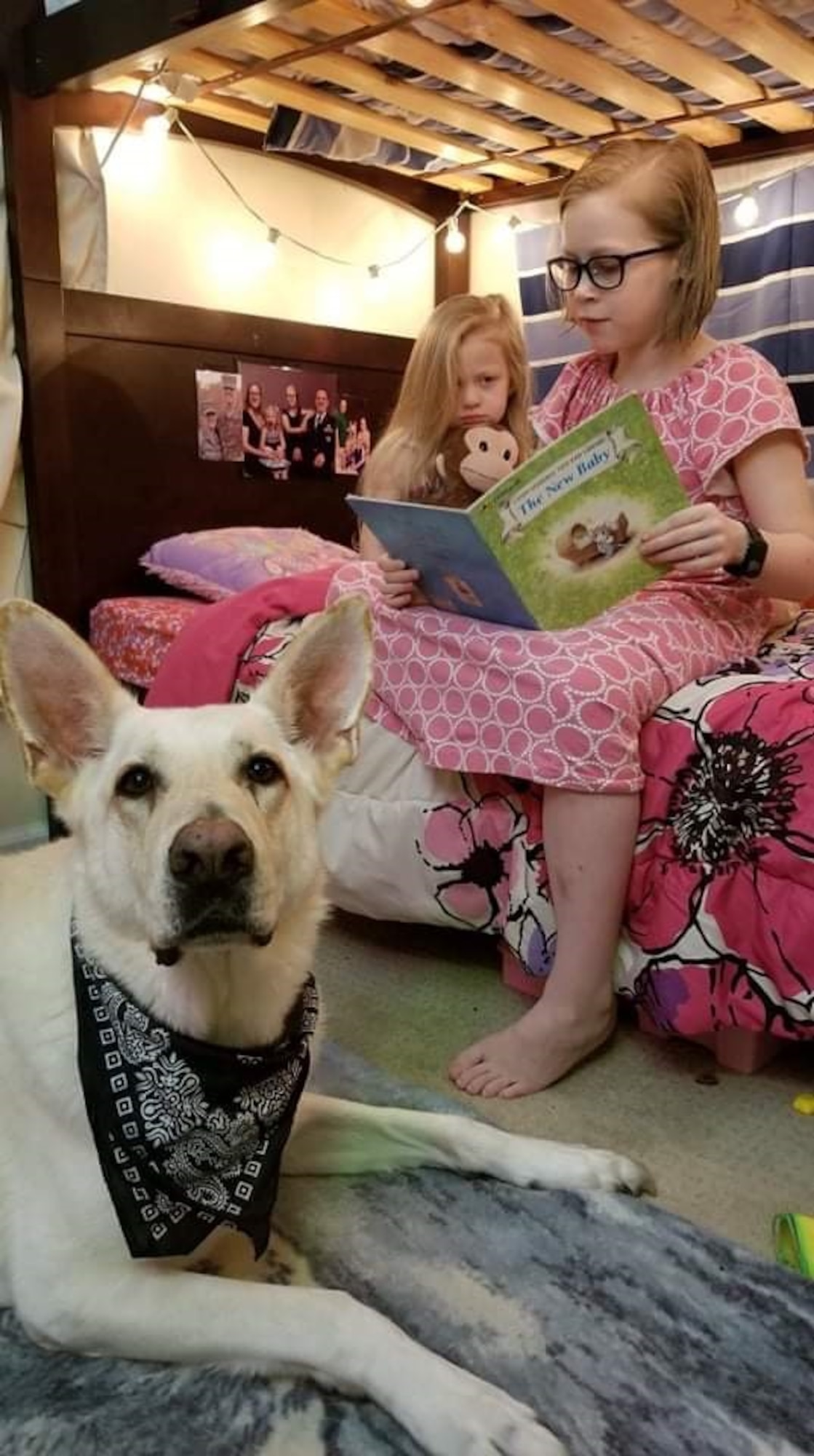 Leo, Kirchner family dog, guards Alyssa, 10, and Isabella, 4, while reading “The New Baby,” Oct. 27, 2019, at their home in Virginia. The two big sisters read the book to prepare themselves for their newborn sister, Emily. (Photo by Sarah Kirchner)