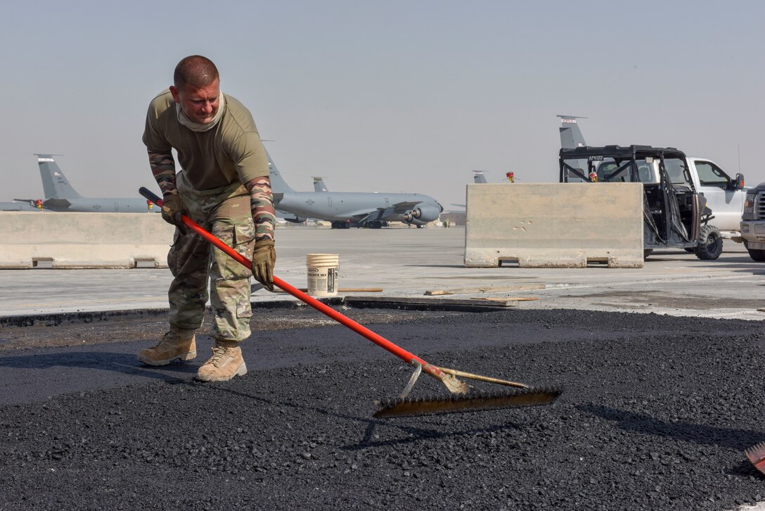An Airman assigned to the 379th Expeditionary Civil Engineer Squadron smooths asphalt while repairing a section of damaged airfield at Al Udeid Air Base, Qatar on April 23, 2020. The Airfield had degraded, creating potential hazard from foreign objects. The 379 ECES monitors airfield conditions and makes needed repairs, enabling the 379th Air Expeditionary Wing to deliver airpower throughout the U.S. Air Forces Central Command area of responsibility. (U.S. Air Force photo by Tech. Sgt. John Wilkes)