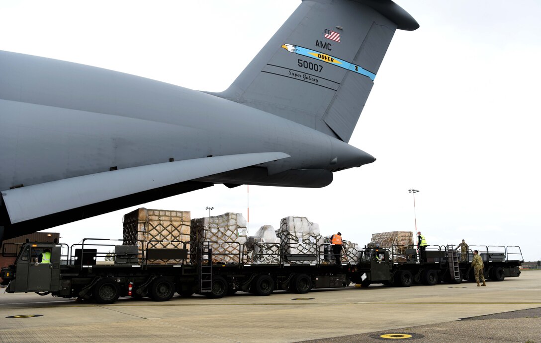 Air mobility Airmen and contractors from the 727th Air Mobility Squadron, RAF Mildenhall, England, push pallets of cargo onto a K-loader off a C-5 Super Galaxy assigned to the 9th Airlift Squadron, Dover Air Force Base, Delaware, during a medical cargo mission at RAF Mildenhall, England, April 18, 2020. The 727th AMS and 9th AS took part in a mission which involved delivering COVID-19 test kits and other equipment to Accra, Ghana, to be distributed throughout the U.S. African Command area of responsibility. (U.S. Air Force photo by Senior Airman Brandon Esau)