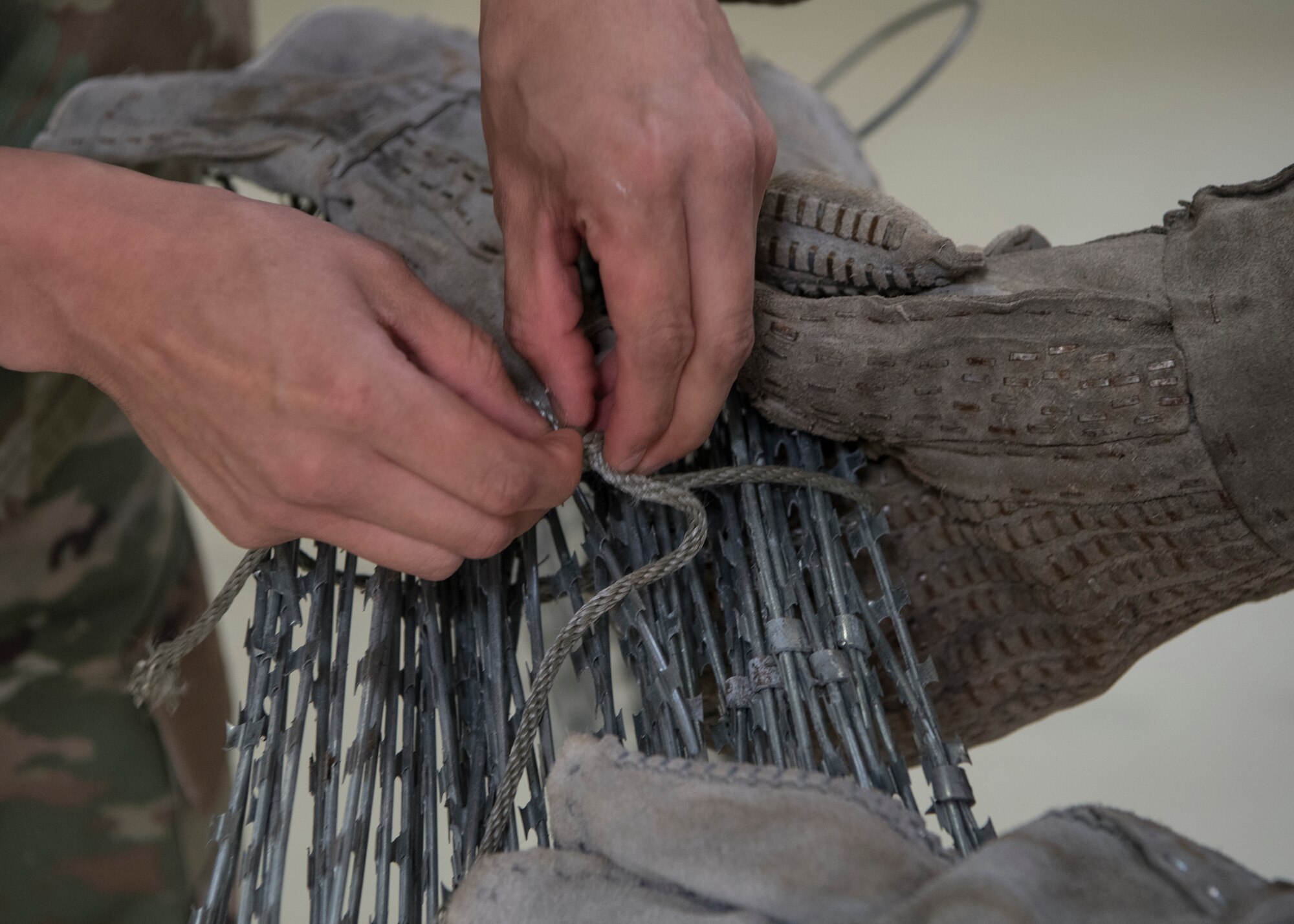 U.S. Air Force Staff Sgt. Abraham Farias, 786th Civil Engineer Squadron expeditionary engineering training manager, unties a roll of razor wire at Ramstein Air Base, Germany, April 23, 2020