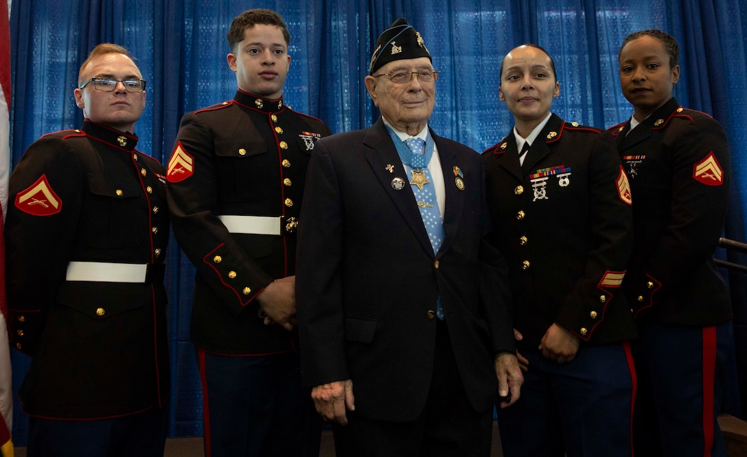 World War II Medal of Honor recipient Hershel Woodrow “Woody” Williams, a retired U.S. Marine, and U.S. Marines with Fleet Marine Force Atlantic, U.S. Marine Corps Forces Command, pose for a photo after the ship commissioning ceremony for the USNS Hershel “Woody” Williams at the Half Moone Cruise and Celebration Center in Norfolk, Virginia, on Mar. 7, 2020. The USNS Hershel “Woody” Williams will serve as a flexible platform to support a variety of missions, including air mine countermeasures, counter-piracy operations, maritime security and humanitarian missions. The Ship is named in honor of Williams for his gallant efforts during the battle of Iwo Jima. (U.S. Marine Corps Photo by Cpl. Desmond Martin)