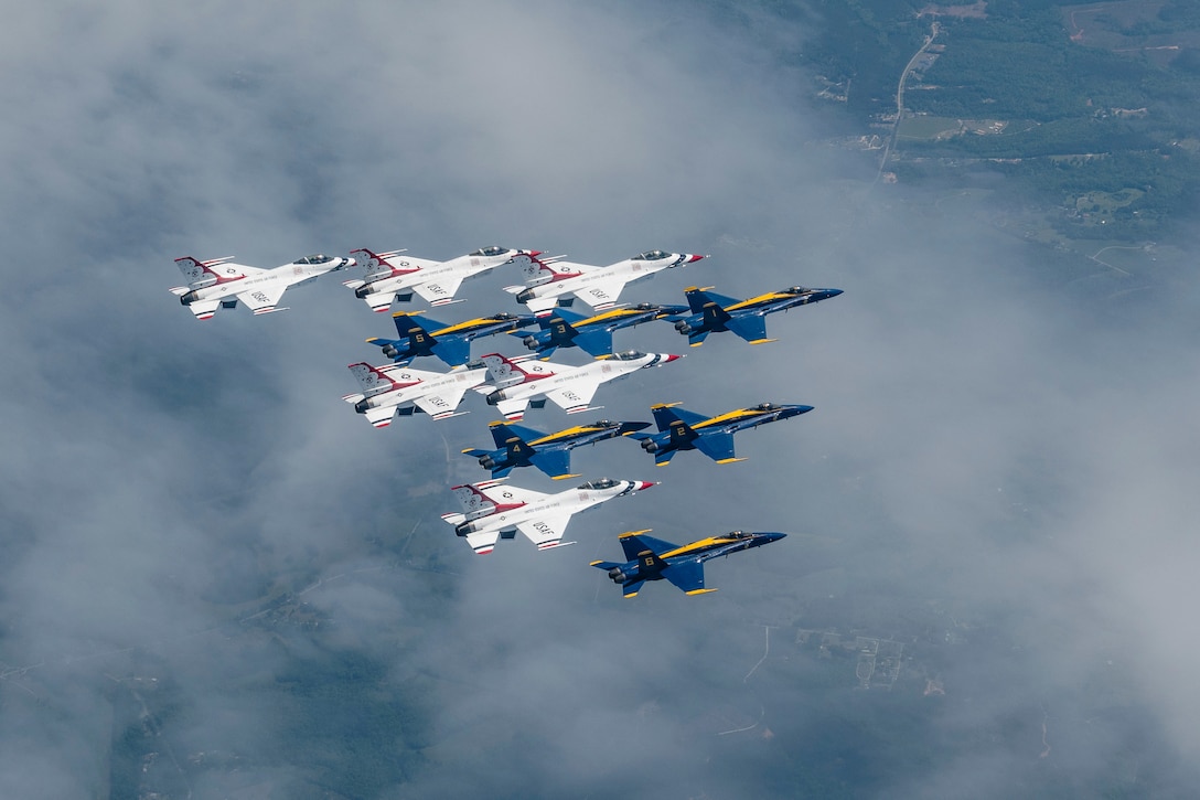 White and blue aircraft fly in a triangular formation in cloudy sky.