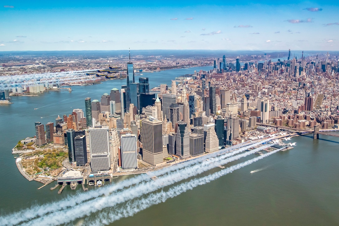 Two formations of aircraft fly by the New York City skyline.