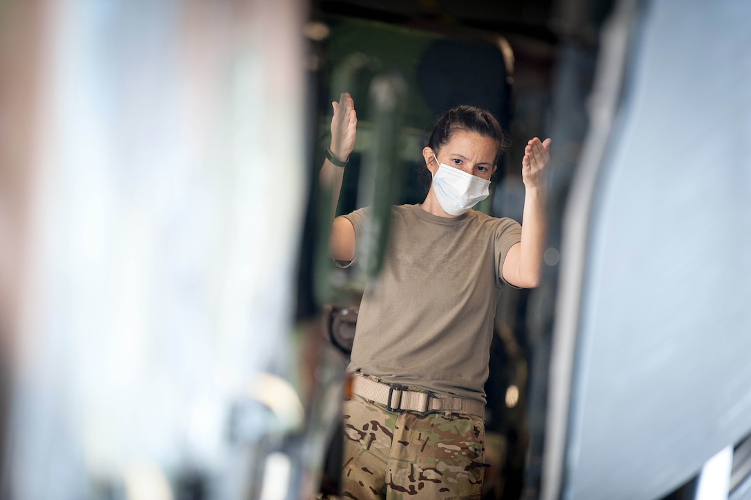 An airman wearing protective gear directs a vehicle.